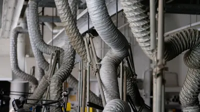 Flexible air ducts hanging from a ceiling in a workspace